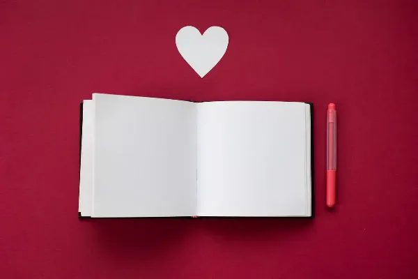 An open notebook with a marker and a small heart beside it