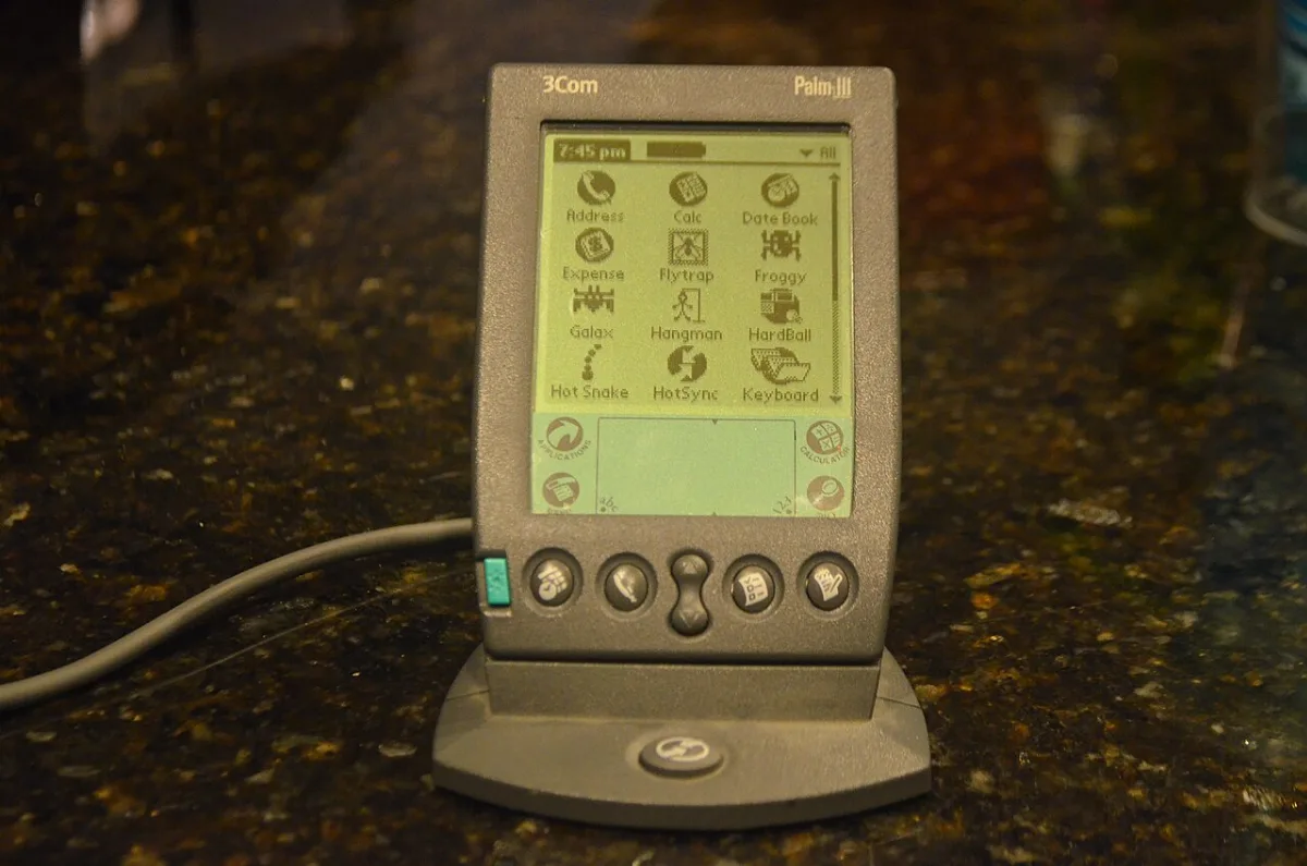A Palm III organizer sitting in its sync cradle