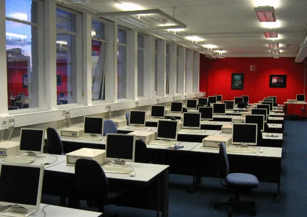 Rows of desktop computers with bulky CRT monitors in a computer lab